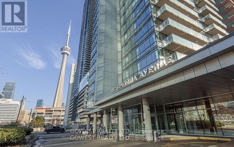 A building with a glass facade and a tall tower in the background.