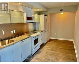 A kitchen with white appliances and wooden floors.