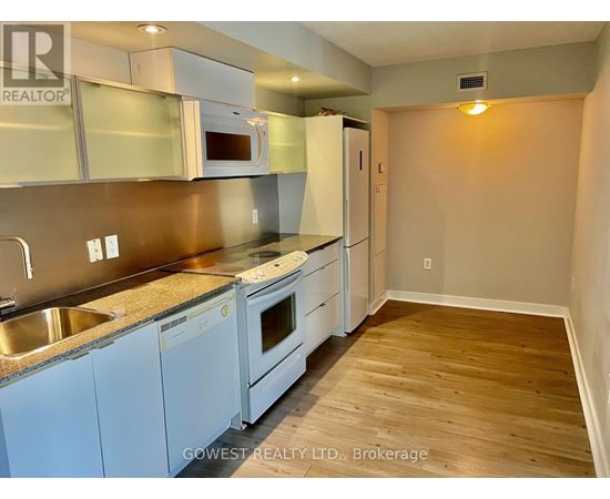 A kitchen with white appliances and wooden floors.
