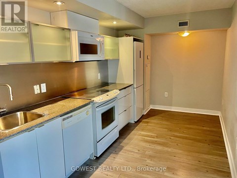 A kitchen with white appliances and wooden floors.