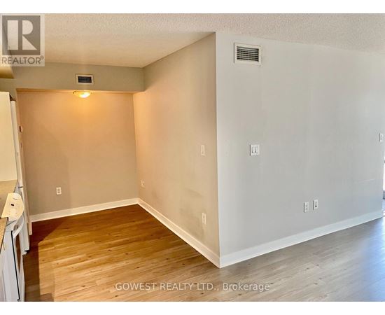 A room with wooden flooring and white walls, with a small light on the wall.
