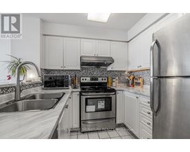 A kitchen with white cabinets and a stainless steel refrigerator.