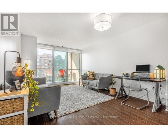 A well-lit, modern living room with a grey sofa, a wooden coffee table, and a large window with a view of the city.