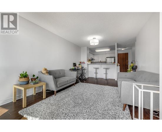 A living room with a grey couch, a grey rug, a wooden table, and a white chair.