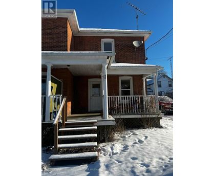 A red brick house with a white porch and stairs leading to the front door.