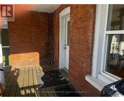 A small porch with a black mat and a white door.