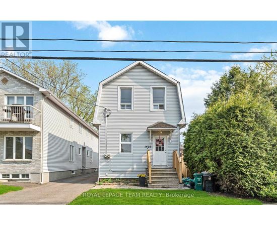 A house with a white facade is for sale, as indicated by the sign on the front.