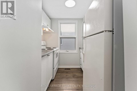 A white refrigerator is in a kitchen with white cabinets.