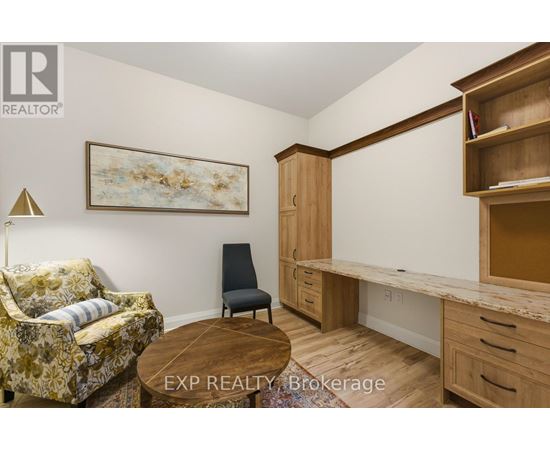 A room with a couch, chair, and desk with EXP Realty Brokerage in the corner.