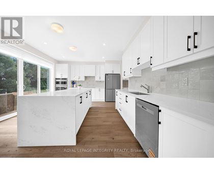 A modern kitchen with white cabinets and a wooden floor.