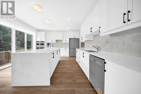 A modern kitchen with white cabinets and a wooden floor.