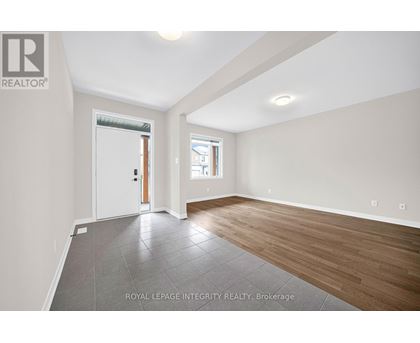 A spacious room with wooden flooring and a sliding glass door leading to a balcony.