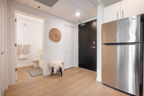 A kitchen with a stainless steel refrigerator and a white chair with a white fluffy cushion.