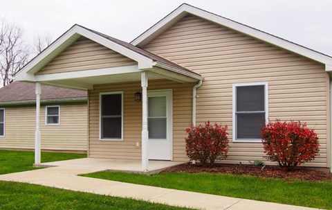 A beige house with a white door and windows.