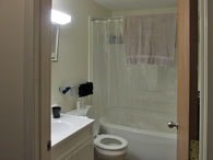 A white toilet sits in a bathroom next to a shower curtain.