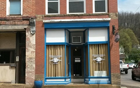 A blue and white storefront with a clock on the window.