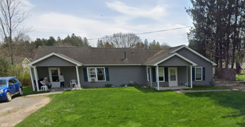 A house with a grey roof and a blue car parked in front.