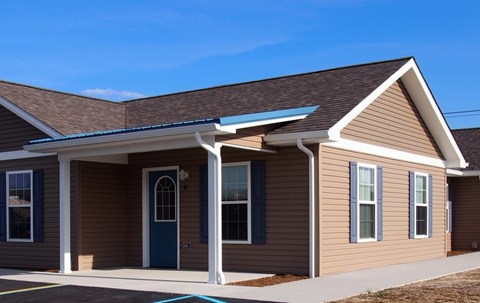 A small house with a brown siding and a blue door.