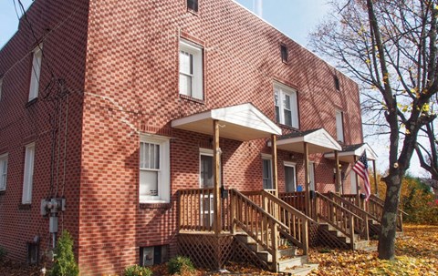 A red brick house with a porch and a flag.