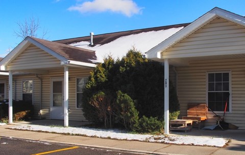 A house with a brown roof and white siding with a small porch.