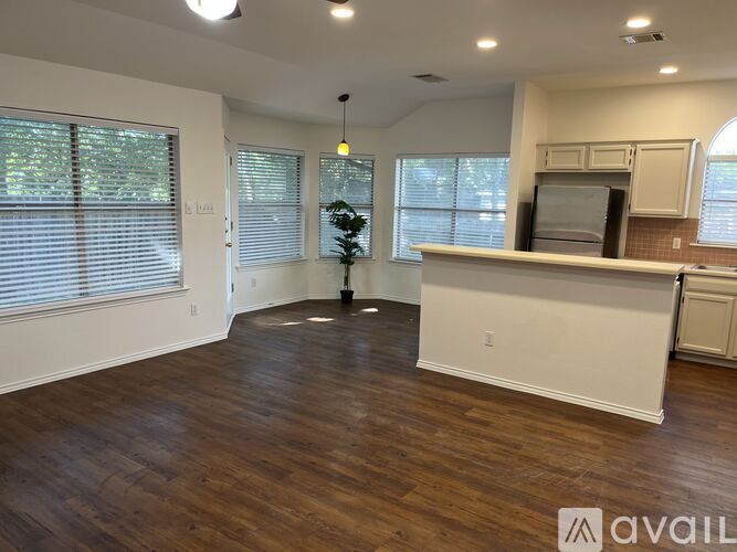 A room with wooden floors and a white countertop with a microwave on it.