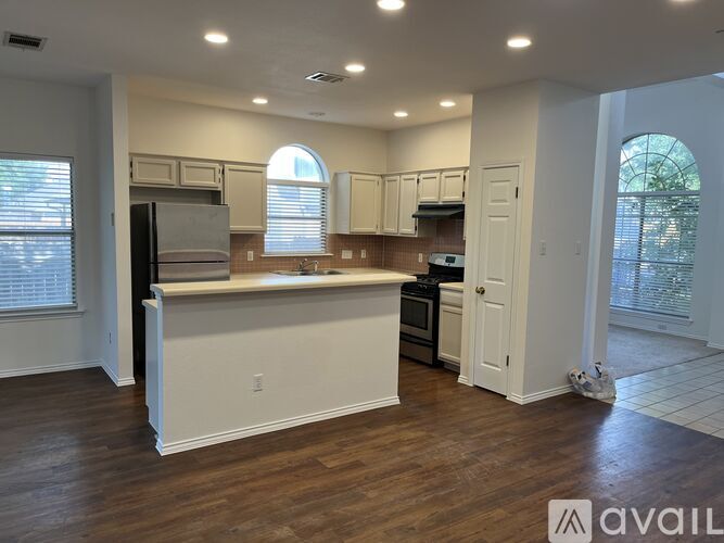 A kitchen with white cabinets and a wooden floor.
