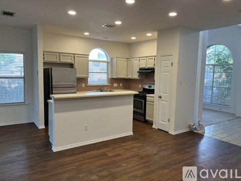 A kitchen with white cabinets and a wooden floor.