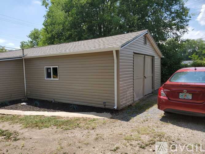 A small house with a red car parked in front.