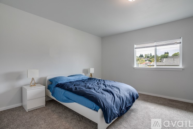 A bedroom with a bed, nightstand, and window.