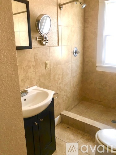 A bathroom with a sink, mirror, and shower.