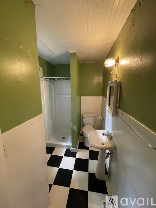 A bathroom with green walls and a black and white checkered floor.