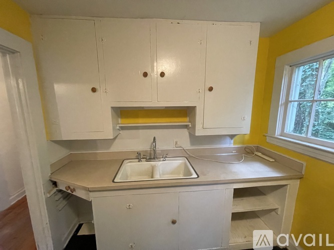 A kitchen with white cabinets and a yellow wall.