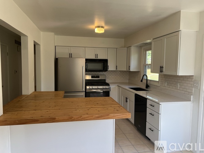 A kitchen with white cabinets and a wooden counter top.