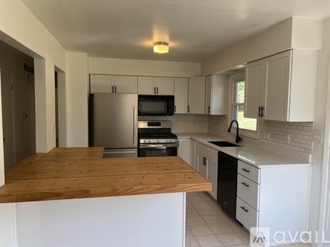 A kitchen with white cabinets and a wooden counter top.