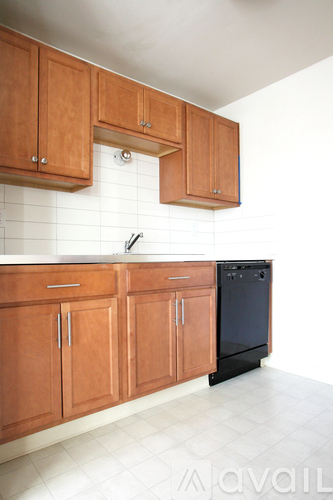 A kitchen with wooden cabinets and a black dishwasher.