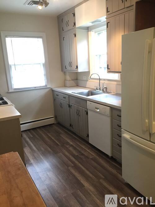 A kitchen with white cabinets and a wooden floor.