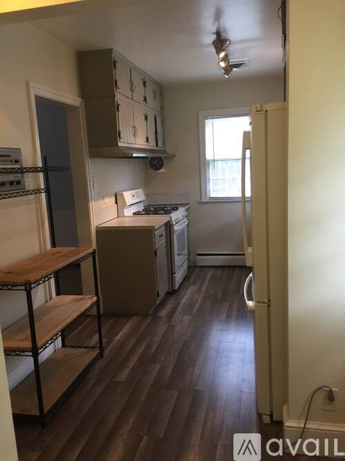 A kitchen with wooden floors and a white refrigerator.