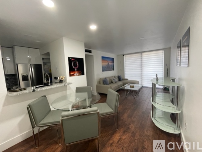 A modern living room with a glass table and grey chairs.