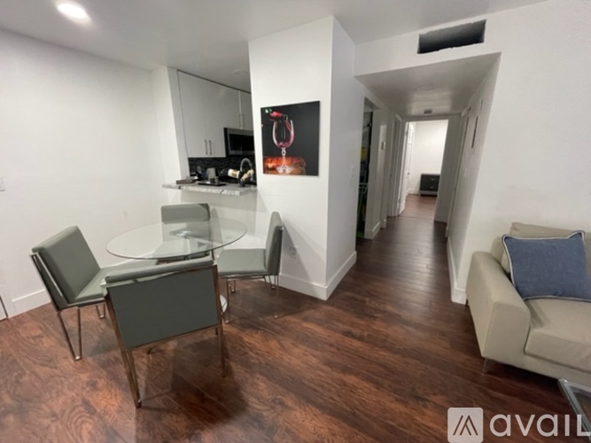A living room with a glass table and grey chairs.