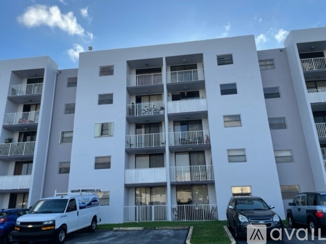 A white apartment building with cars parked in front.