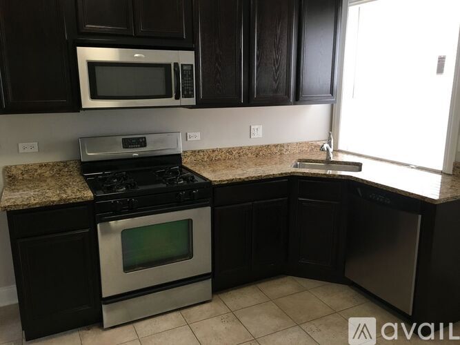 A kitchen with black cabinets and a granite countertop.