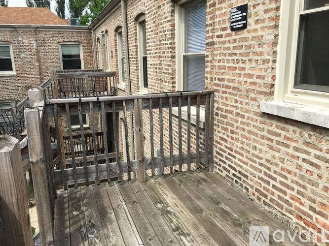 A wooden gate leads to a brick building with a plaque on the wall.