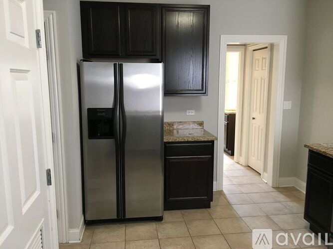 A kitchen with a black fridge and cabinets.