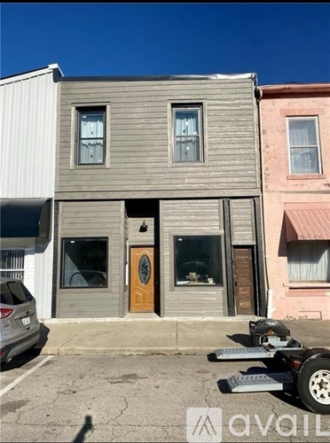 A grey house with a brown door is in front of a pink house.