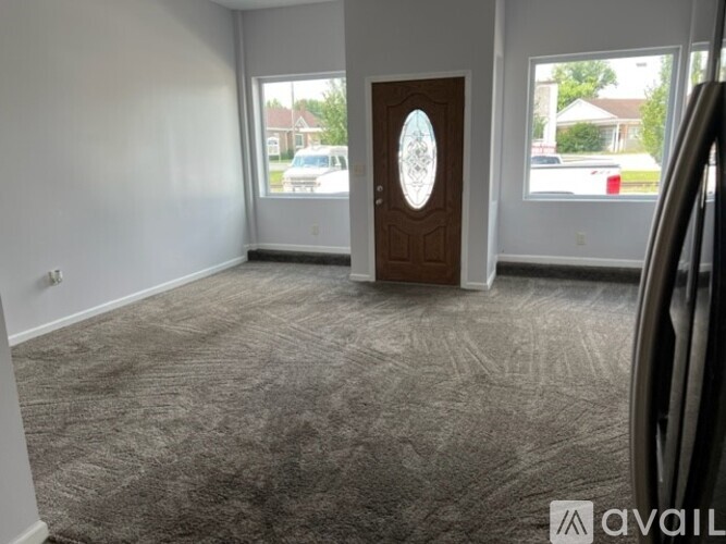 A room with a carpeted floor and a wooden door with a circular design in the middle.