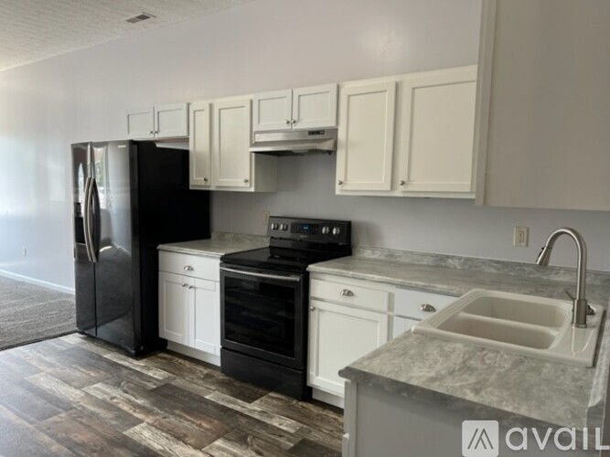 A kitchen with black appliances and white cabinets.