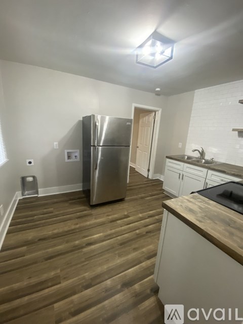 A kitchen with a refrigerator and wooden floors.
