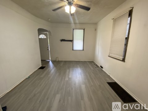 A room with a ceiling fan and a door on the left side.