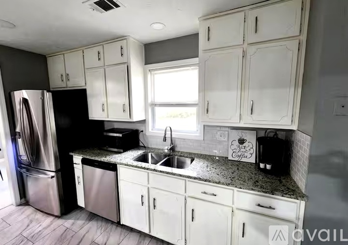 A kitchen with white cabinets and a black refrigerator.