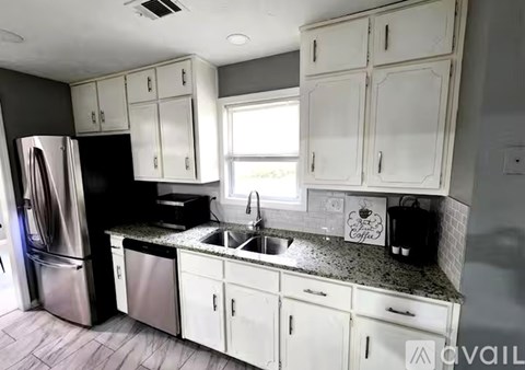 A kitchen with white cabinets and a black refrigerator.